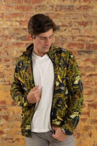 Front view close up of a young Caucasian man wearing casual street fashion clothes standing against a brick wall and looking down